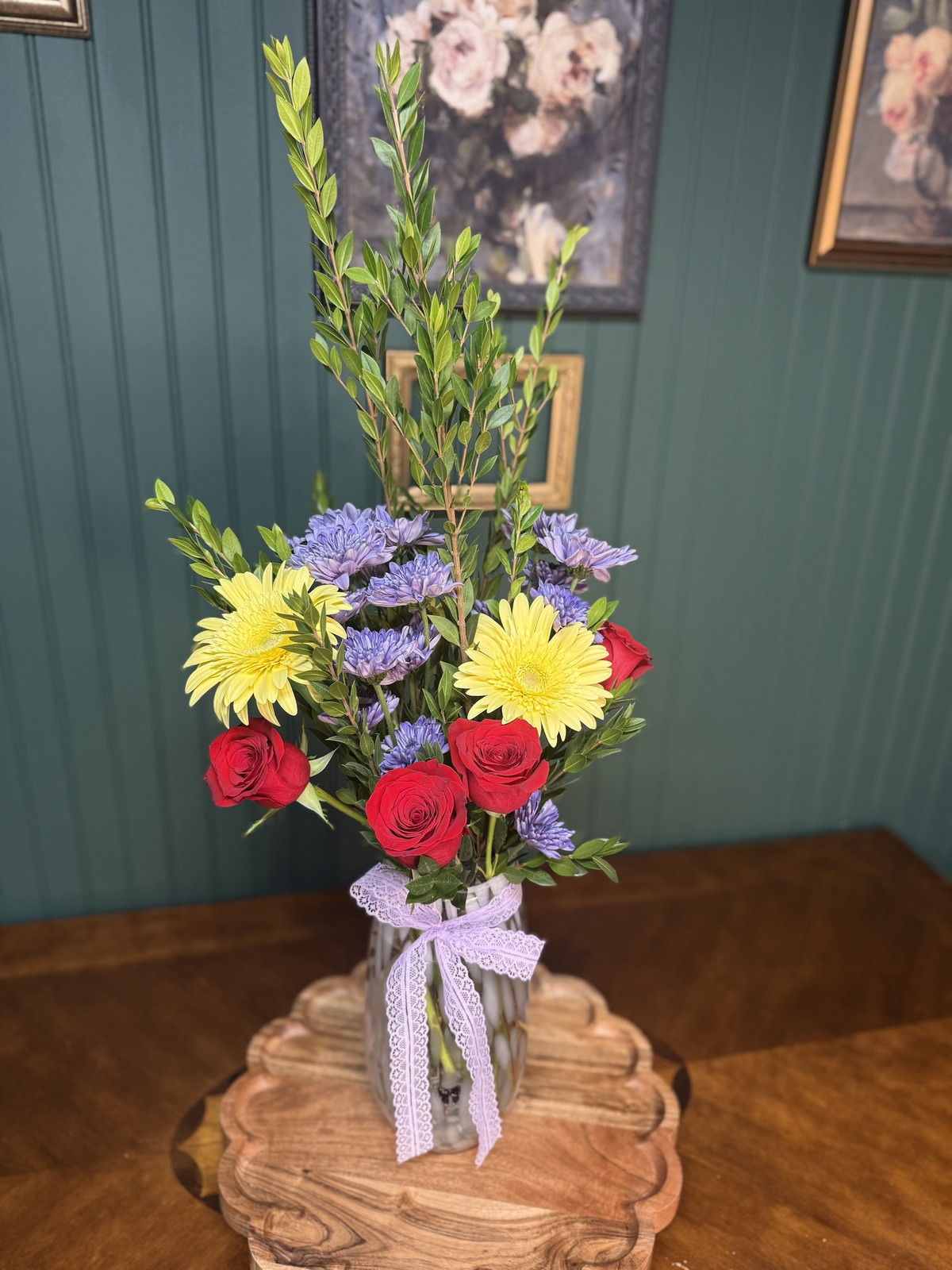 Red roses, yellow gerberas and lavender mums with tall myrtle in a speckled vase