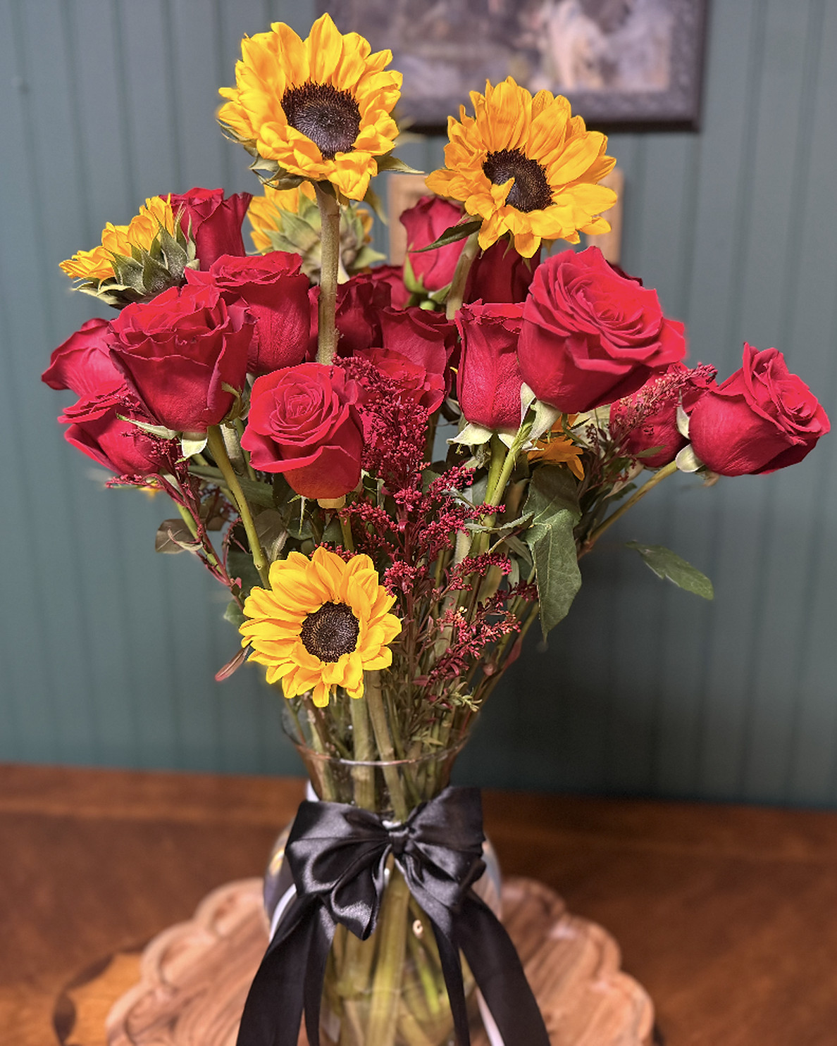Red roses and sunflowers in a vase tied with a black satin bow