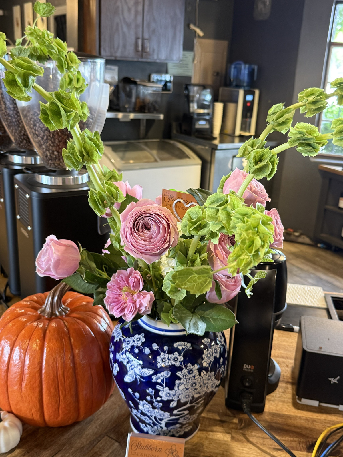 Pink ranunculus and roses with bells of Ireland in a blue-and-white ginger jar